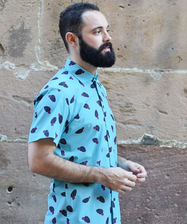 Camisa estampada, de hombre, de manga corta, hecha en algodón orgánico, con estampado de corazones sobre fondo turquesa.