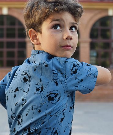 Camisa de niño, de manga corta, con estampado de acróbatas sobre fondo azul. Hecha en algodón orgánico