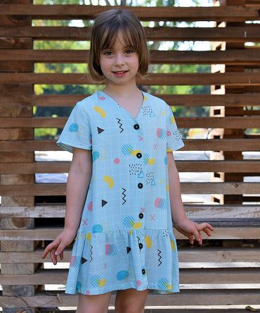Vestido infantil geométrico, de manga corta, hecho en viscosa, con estampado de cuadrícula y motivos geométricos sobre fondo celeste.