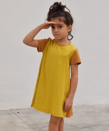 Vestido infantil Curry, hecho en algodón orgánico, de manga corta, combina color curry en el delantero y color ocre en mangas y trasero. Hecho en España.
