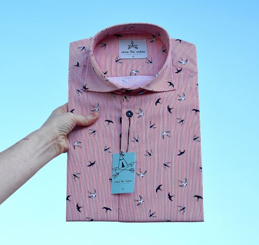 Camisa estampada de hombre, de manga corta, hecha en algodón, con estampado de golondrinas y fondo a rayas rojas y blancas. Hecha en España de manera sostenible y bajo condiciones laborales éticas.