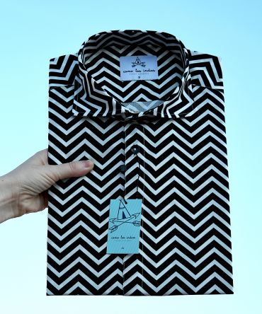 Camisa estampada de hombre, de manga corta, hecha en algodón orgánico, con bonito estampado de rayas negras en zig zag sobre fondo blanco. Tiene bajo recto y cuello tipo italiano.