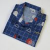 Camisa de niño estampado geométrico sobre fondo azul. Es de manga corta y está hecha en algodón orgánico, de manera sostenible.