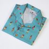 Camisa de niño estampada con chicas hula sobre fondo turquesa. Es de manga corta y está hecha en algodón orgánico, de manera sostenible.
