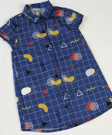 Vestido camisero de niña, de manga corta, hecho en algodón orgánico con estampado geométrico y fondo azul. Hecho en España.